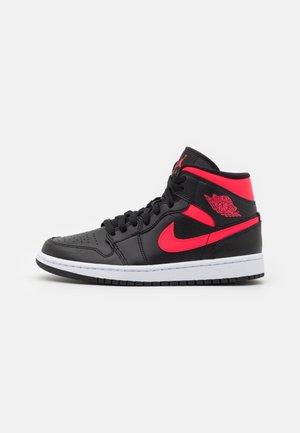 Czarno-czerwony wysoki sneaker z logo Nike swoosh i logo Air Jordan wings po boku, biała środkowa podeszwa i czarna zewnętrzna podeszwa.