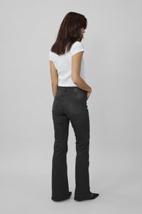 Fitted black flared jeans with a slightly faded texture, 5-pocket design, and a mid-rise waist, paired with a white short-sleeve top.