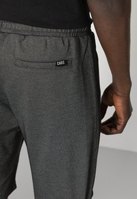 Grijze sportshorts gemaakt van structuurstof, met een elastische tailleband en een achterzak met een zwart label met de tekst "CARS."