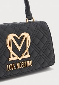 Schwarze, gesteppte Handtasche mit goldfarbenem, herzförmigem "M"-Logo und dem Text "LOVE MOSCHINO" auf der Vorderseite, mit einem kurzen schwarzen Ledergriff.