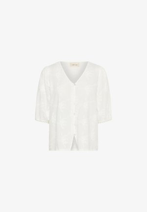 Blouse blanche avec un col en V, manches courtes bouffantes, fermeture par boutons et un motif floral gaufré sur toute la surface. Fines bordures en dentelle sur les manches.