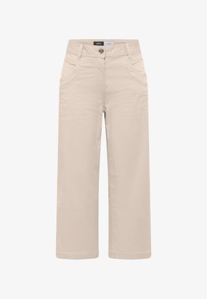 Beżowe spodnie o szerokich nogawkach z przednimi kieszeniami, szlufkami na pasek, zapięciem na guzik oraz widoczną metką marki „CECIL” na pasku w talii.