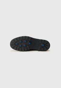 Black rubber shoe sole featuring a textured pattern with six blue circular accents and a multi-directional tread design for traction.