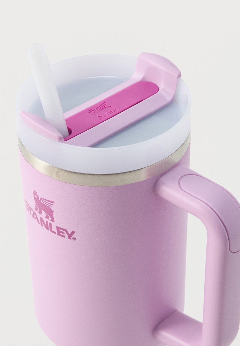 Taza aislante rosa con asa, tapa blanca y tapa deslizante rosa a juego para la pajita con una pajita insertada.