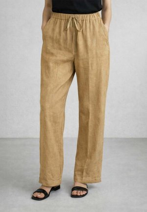 Pantaloni beige in lino a gamba dritta con vita elasticizzata e coulisse, indossati con top nero senza maniche e sandali neri aperti sulle dita.