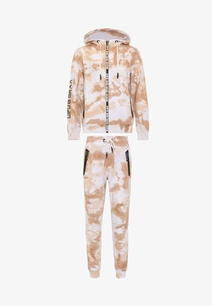 Two-piece tracksuit in beige and white tie-dye print. The hoodie features a front zipper, drawstrings, and printed accents. Pants have side pockets.