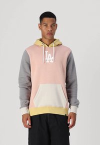 Sudadera con capucha de diseño en bloques de color rosa y gris, que presenta un logo blanco, un bolsillo frontal tipo canguro y una capucha con cordón amarillo.