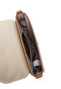 Kabelka v tanovém odstínu s béžovou plátěnou vnější stranou. Uvnitř má hnědý podšívkový vzor s puntíky, obsahuje vnitřní kapsu a štítek, což zdůrazňuje strukturovaný design.