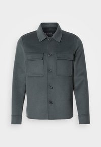 Dark grey jacket made of soft fabric, featuring a button-up front, two chest pockets, and a collared neckline with folded cuffs.