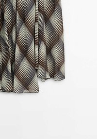 Jupe à carreaux marron et beige en tissu léger et fluide, suspendue sur un fond blanc.
