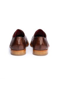 Paar polierter brauner Herrenschuhe aus Leder mit Holzabsätzen, von hinten auf weißem Hintergrund gesehen.