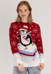 Red sweater featuring a penguin graphic wearing a hat and scarf, snowflakes, and contrasting white ribbed cuffs and hem.