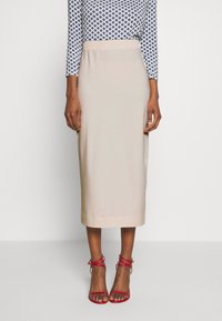 Světlá béžová midi sukně s elastickým pasem. Spárovaná s červenými sandály na tenkých řemíncích. Top má modrý geometrický vzor.