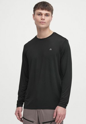 Black long-sleeve shirt made of smooth fabric, featuring a crew neckline and a small white logo on the chest, paired with light gray shorts.