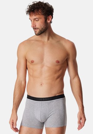 Graue Boxershorts mit einem schwarzen Bund, der das "Schiesser"-Logo trägt. Glatte Textur, enganliegendes Design, kurze Beine und klassischer Schnitt.