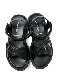 Czarne sandały na płaskiej podeszwie, z wieloma paskami i srebrnym akcentem w postaci klamry. Wykonane z gładkiej skóry, z teksturowaną wkładką.