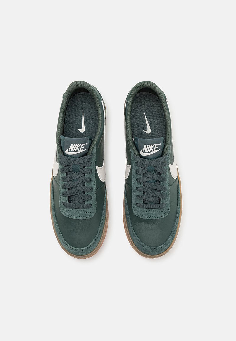 Zapatillas de cuero verde oscuro con el swoosh blanco de Nike, cordones texturizados y suela de goma marrón. Presenta un interior acolchado y el logo en la lengüeta.