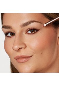 Brązowe oczy z wyraźnymi rzęsami i naturalnie wyglądającą skórą. Użyto metalicznego ołówka do podkreślenia górnej powieki. Neutralny kolor ust.