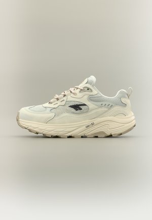 Zapatilla con parte superior de malla ligera en crema y azul claro, detalles texturizados, un logo negro y suela blanca acolchada.