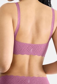 Bezdrôtová podprsenka z jemného levanduľového materiálu s textúrovaným geometrickým vzorom, širokým okrajom s vlnkovaným vzorom a nastaviteľnými ramienkami.