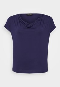 Marinblå kortärmad topp med draperad uringning och en svart etikett där det står "ANNA FIELD" inuti kragen.