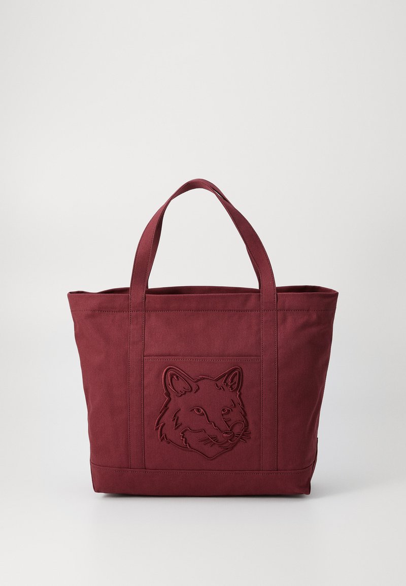 Μαρούν τσάντα ώμου φτιαγμένη από ανθεκτικό ύφασμα, με ανάγλυφη σχεδίαση κεφαλής αλεπούς μπροστά, και στιβαρές λαβές για εύκολη μεταφορά.