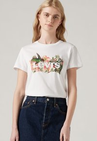 Camiseta de algodón blanca con un gráfico floral colorido y el texto "Levi's", cuello redondo y mangas cortas.