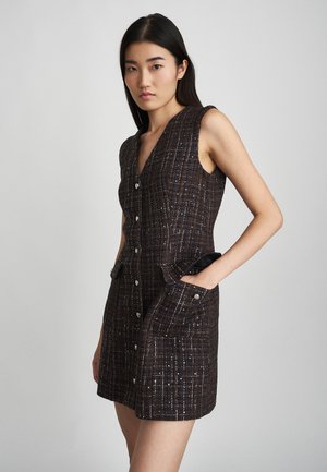 Robe sans manches en tissu brun texturé avec un motif à carreaux. Présente des boutons sur le devant et deux poches latérales.
