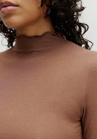 Bruine geribbelde turtleneck met een gerimpelde halslijn, aansluitend ontwerp, zachte textuur en effen oppervlak, dat een subtiele glans tegen de huid toont.