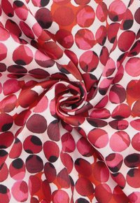 Red and pink fabric with a dot pattern, featuring varying sizes of circles. Soft texture, lightweight material, and a cream background.