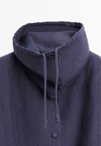 Granatowa kurtka z wysokim kołnierzem, ozdobiona guzikami pokrytymi tkaniną oraz regulowanym sznurkiem przy kołnierzu.