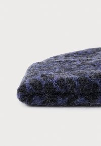 Sciarpa di lana lavorata a maglia in grigio scuro e blu navy con un motivo testurizzato. Piegata, mostra le fibre morbide e un aspetto accogliente e caldo.