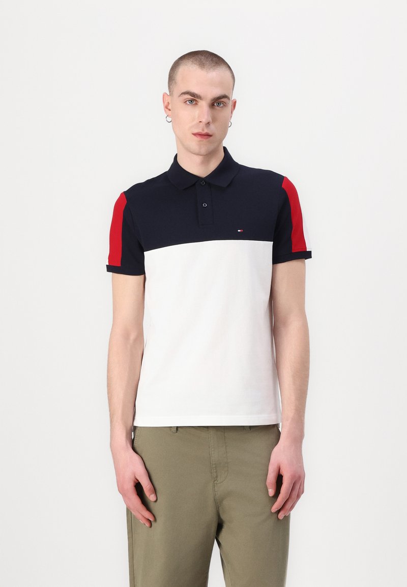 Polo skjorte med marineblå overdel, hvit midtdel og røde ermer. Laget av bomull, med kragedesign og korte ermer.