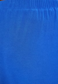 Blauwe stof met een fijne ribbelstructuur en elastische tailleband, met een effen kleur zonder zichtbare patronen of extra details.