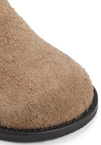 Tan mockasinfodrade ankelstövlar med en mjuk textur och rund tå. Svart gummisula med en minimalistisk design och utan synlig hårdvara.