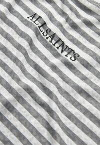 Šedá a biela pruhovaná tkanina s jemným leopardím vzorom, s názvom značky "ALLSAINTS" vyšitým v čiernej farbe. Mäkka textúra.