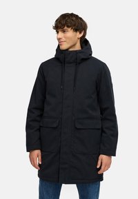 Zwarte parka jas met een capuchon, voorzien van een ritssluiting aan de voorkant, twee voorzakken en verstelbare trekkoorden. Gemaakt van glad, duurzaam materiaal.
