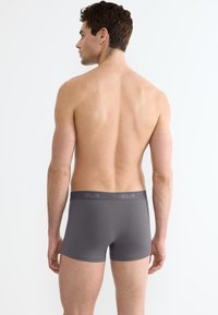 Boxer shorts grigi con un materiale morbido, dotati di un elastico in vita con un discreto dettaglio del logo. Texture liscia e design aderente.