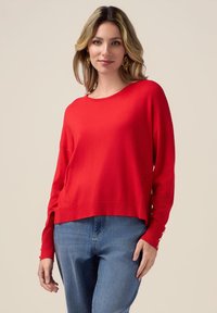 Maglione rosso lavorato a maglia con una vestibilità comoda, scollo rotondo e tasche laterali; presenta dettagli con bottoni sulle maniche e un orlo cropped.