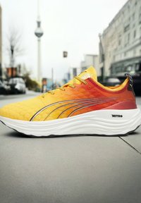 Zapatillas de running con un diseño degradado en amarillo y naranja, que presentan un upper texturizado, acentos en plata y una gruesa suela blanca.
