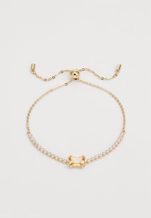 Bracciale d'oro con una pietra dorata rettangolare centrale, circondata da cristalli rotondi trasparenti, su una delicata catena con chiusura regolabile.