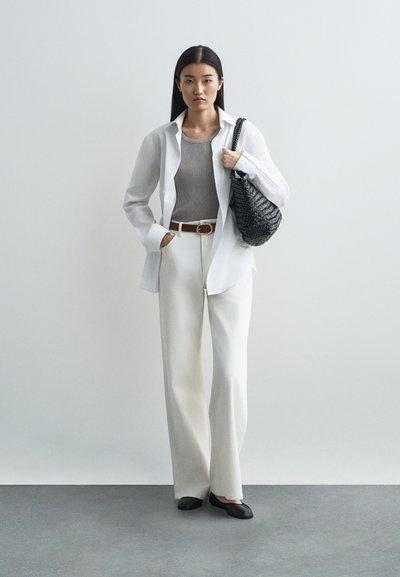 Balta pogā, pelēks ribots topiņš, krēmbalti plati bikses, melna austs plecu soma un melni dzīvokļi. Gluda auduma un kontrastējošas krāsas.