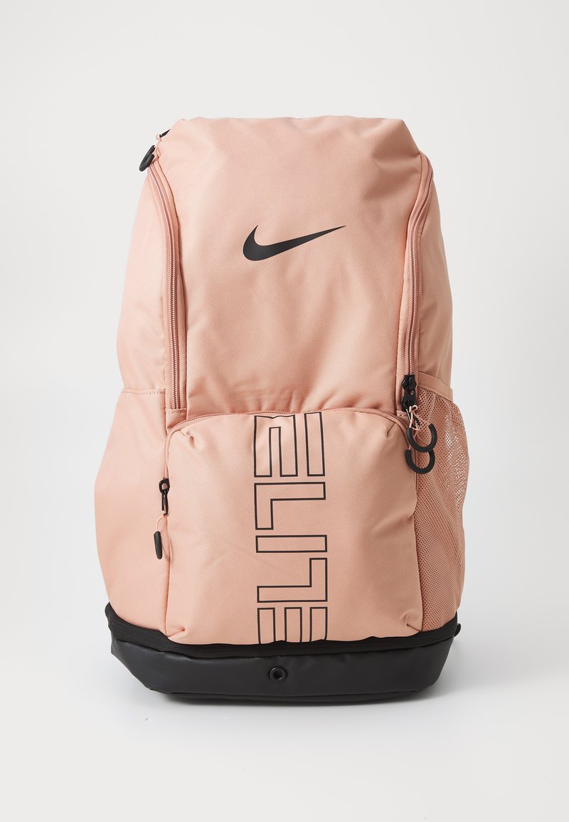 Mochila Nike en suave material rosa claro que presenta un gran zipper principal, llamativo texto negro "ELITE" y una base negra en la parte inferior con un bolsillo lateral de malla.