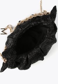 Bolso de mano tejido en negro con una superficie texturizada, que cuenta con una correa de cadena dorada y un charm decorativo en forma de 'M'. El interior tiene un forro negro.