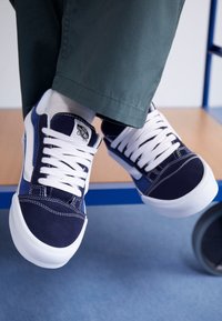 Marineblaue Leinensneaker mit weißen Schnürsenkeln, gepolstertem Zunge, kontrastierenden Nähten und weißer Gummisohle.