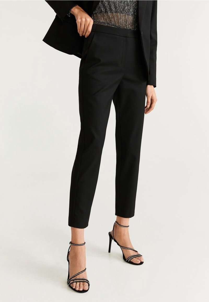 Czarne spodni z wąskim krojem, o gładkiej fakturze i długości do kostek. Połączone z czarnymi sandałami na wysokim obcasie z paskami.