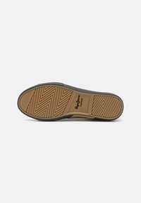 Semelle de chaussure avec une bande de roulement en caoutchouc brun, montrant des motifs en zigzag et rayés et le texte de la marque au centre sur un fond clair.