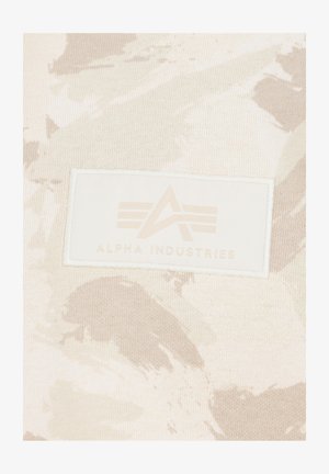 T-shirt beige chiaro con un sottile motivo camouflage, caratterizzato da un'etichetta rettangolare bianca con il logo impresso "Alpha Industries".