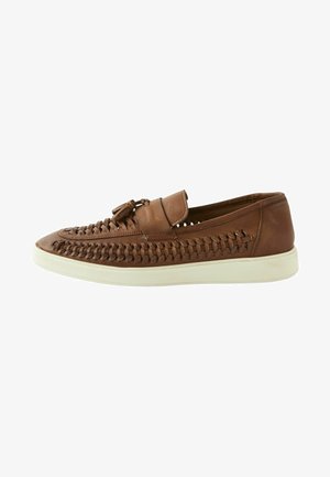 Brown leather slip-on shoes featuring woven detailing, a flat white sole, and a small front strap with a decorative bow.