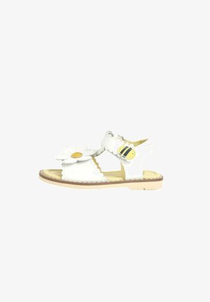 Weiße Leder-Sandale mit Blumenakzent, verstellbarem Riemen, flacher Sohle und gewelltem Rand. Leichtes Design, geeignet für den Sommer.